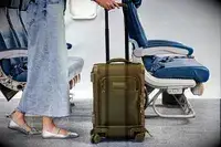 A person wheeling the Dagne Doverr Seattle Carry On Rolling Luggage 20.5