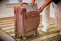 A person places a laptop into the front pocket of the Dagne Dover Smaller Seattle Carry-on Luggage 20.5 Inches