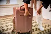 A person reaches inside the back pocket on the Dagne Dover Smaller Seattle Carry-on Luggage 20.5 Inches