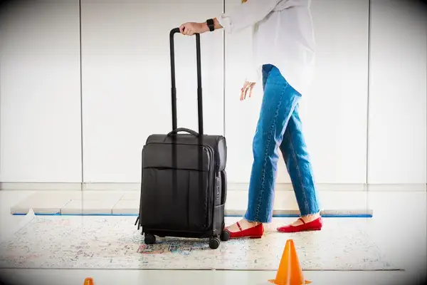 A person walking with the Calpak Luka Soft-Sided Carry-On Luggage on a rug