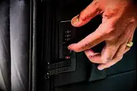 A hand touching the lock on the Calpak Luka Soft-Sided Carry-On Luggage