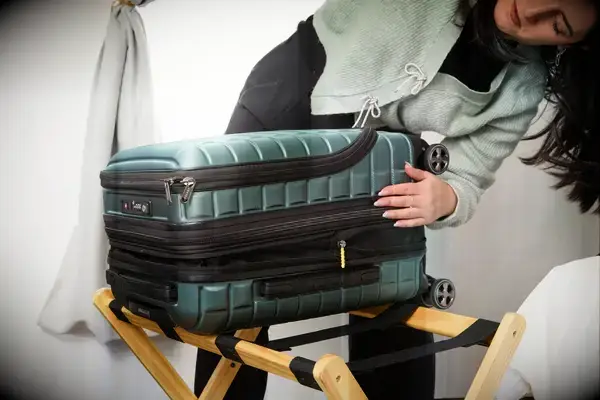 A person examines the zipper on the side of the Delsey Paris Shadow 5.0 Carry-on with Laptop Compartment