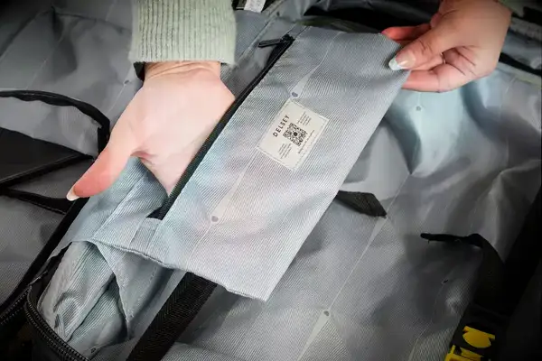 A person places their hand in the pocket of the Delsey Paris Shadow 5.0 Carry-on with Laptop Compartment