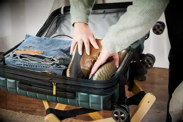 A person places boots into the Delsey Paris Shadow 5.0 Carry-on with Laptop Compartment