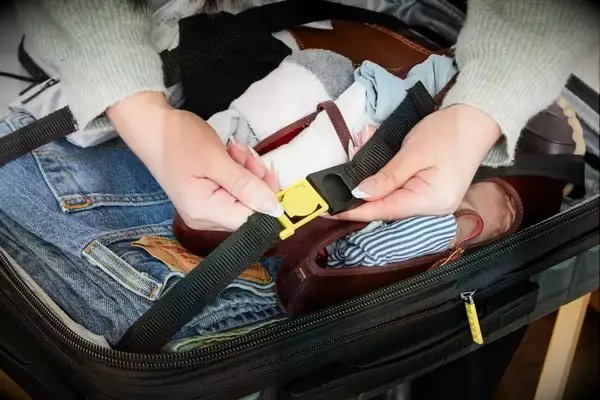 A person secures a strap lock on the Delsey Paris Shadow 5.0 Carry-on with Laptop Compartment