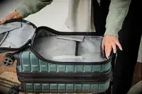 A person holds open the front pocket on the Delsey Paris Shadow 5.0 Carry-on with Laptop Compartment