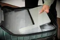 A person places a laptop into a pocket in the Delsey Paris Shadow 5.0 Carry-on with Laptop Compartment