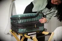 A person examines the zipper on the side of the Delsey Paris Shadow 5.0 Carry-on with Laptop Compartment