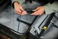 A person adjusts the lock on the Delsey Paris Shadow 5.0 Carry-on with Laptop Compartment