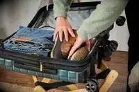 A person places boots into the Delsey Paris Shadow 5.0 Carry-on with Laptop Compartment