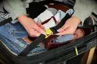 A person secures a strap lock on the Delsey Paris Shadow 5.0 Carry-on with Laptop Compartment