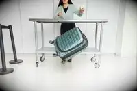 A person throws the Delsey Paris Shadow 5.0 Carry-on with Laptop Compartment off of a wheeled cart