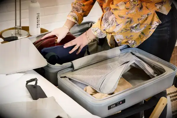 A person packs the Monos Expandable Carry-on Pro