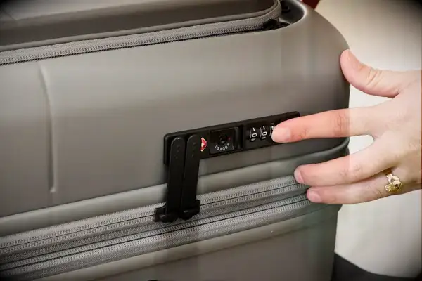 A person presses the lock on the side of the Monos Expandable Carry-on Pro