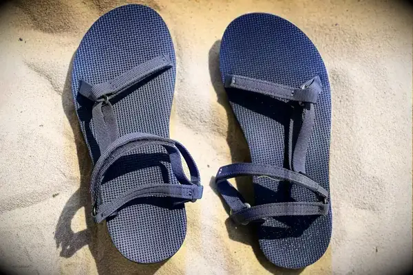 Top view of the Teva Original Universal Slim Sandal with sand as the background