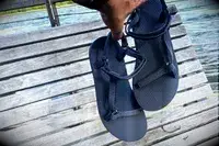A person holding the Teva Original Universal Slim Sandal against a wood background
