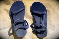 Top view of the Teva Original Universal Slim Sandal with sand as the background