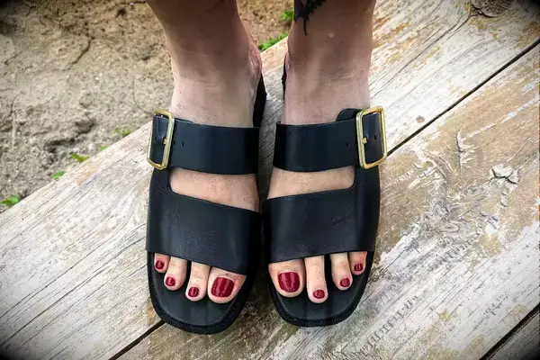 Top view of a person wearing the Franco Sarto Taziana Espadrille Slide Sandals on a wood background