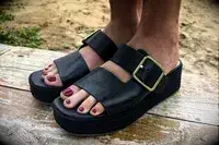 Close up view of a person wearing the Franco Sarto Taziana Espadrille Slide Sandals on a wood background