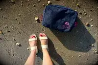 Top view of a person wearing the Bared Footwear Sanderlings on the sand with a bag