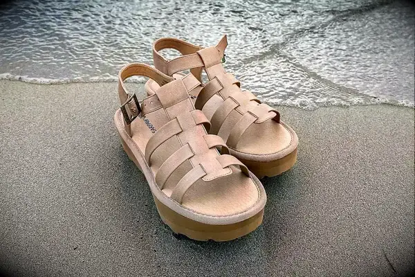 Bear Paw High Seas Iced Coffee Sandals on the sand with water creeping onto shore