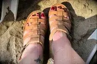 A person wearing the Bear Paw High Seas Iced Coffee Sandals in the sand