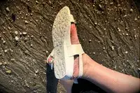 A person wearing the Bared Footwear Sanderlings showing the bottom of the shoe in the sand