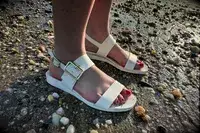 Side view of a person wearing the Bared Footwear Sanderlings on the sand