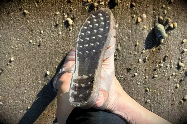 a person wearing the Melissa Possession Jelly Fisherman Sandal showing the bottom of the shoe on the sand