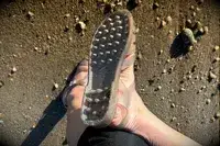 a person wearing the Melissa Possession Jelly Fisherman Sandal showing the bottom of the shoe on the sand