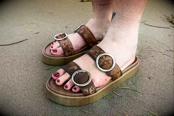 A person wearing the Beek Warbler Leather Platform Platform Leather Slides on the sand
