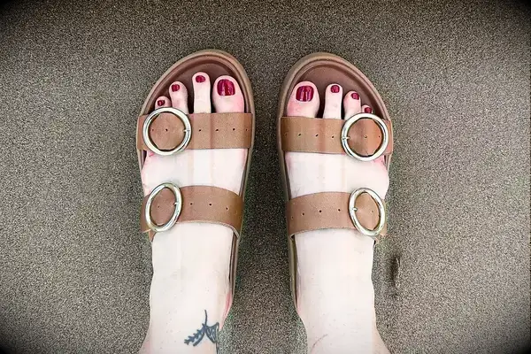 A person wearing the Beek Warbler Leather Platform Platform Leather Slides on sand