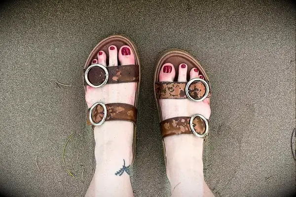 A person wearing the Beek Warbler Leather Platform Platform Leather Slides on sand