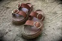 Beek Warbler Leather Platform Platform Leather Slides covered in sand with a sand background