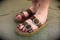 A person wearing the Beek Warbler Leather Platform Platform Leather Slides on the sand