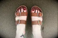 A person wearing the Beek Warbler Leather Platform Platform Leather Slides on sand