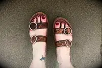 A person wearing the Beek Warbler Leather Platform Platform Leather Slides on sand