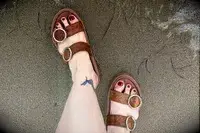 A person wearing the Beek Warbler Leather Platform Platform Leather Slides in the sand