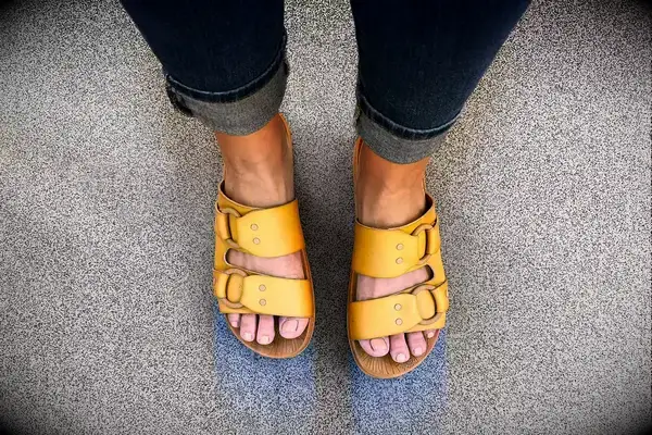 Feet wearing Reef Cushion Vera Cruz Slides on a gray surface