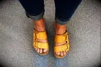 Feet wearing Reef Cushion Vera Cruz Slides on a gray surface