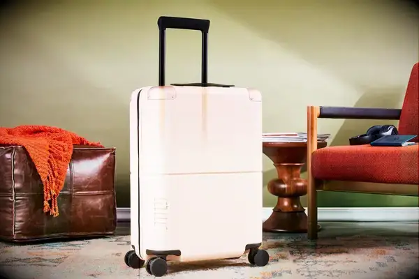 July Carry On displayed between a chair and leather pouf