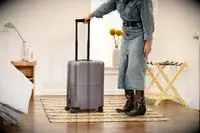 A person rolls the July Carry-on Max over a rug