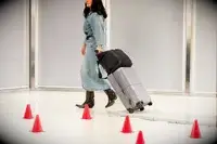 A person rolls the July Carry-on Max over stone pavers