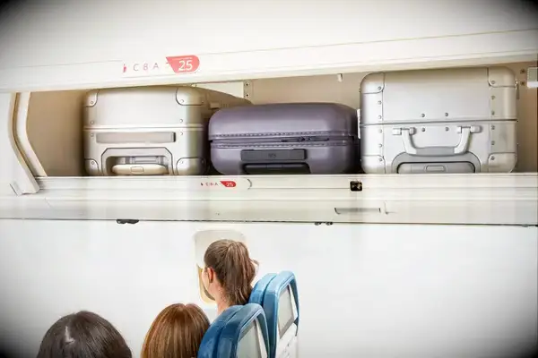 Three suitcases in an overhead bin of an airplane