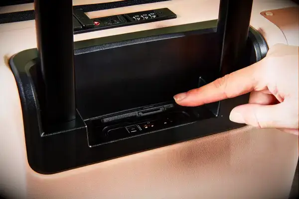 Finger opening the lid for the USB ports on the July Carry On