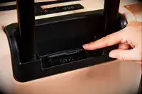 Finger opening the lid for the USB ports on the July Carry On