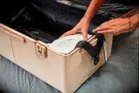 Hands place clothing into the Checked Trunk from the July Trunk Set