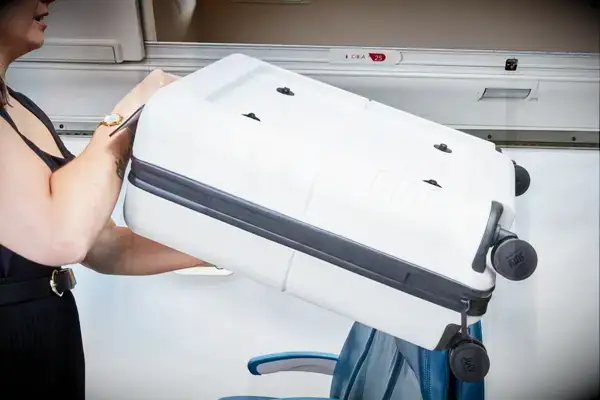 person putting the July Carry On Pro into the overhead compartment of an airplane