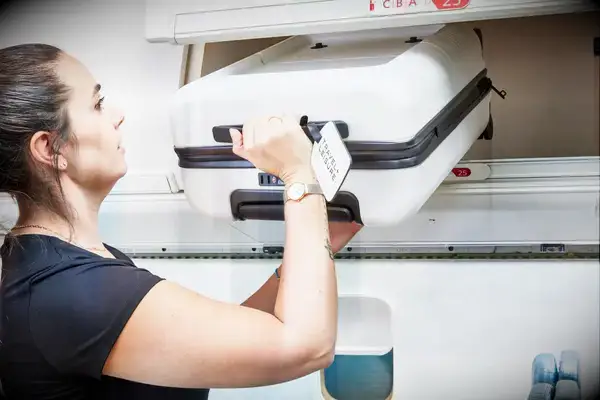 Person putting July Carry On Pro SnapSleeve into the overhead compartment of an airplane