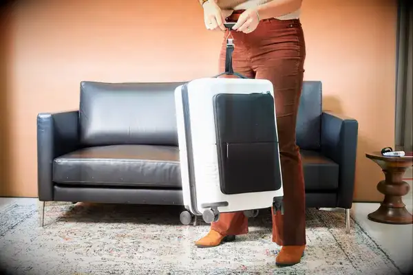 A person uses a luggage scale to weight a July Carry On Pro SnapSleeve